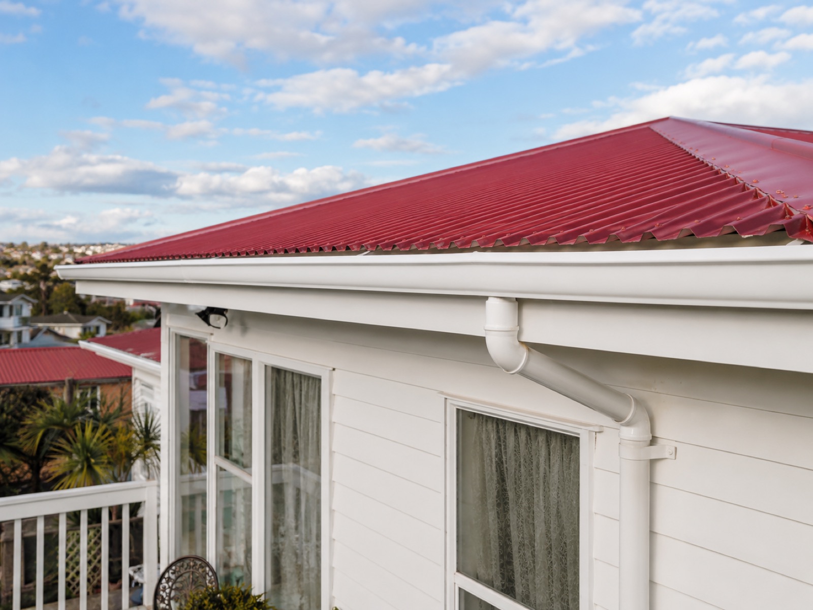 Black continuous spouting and downpipe on a contemporary trapezoidal roof above a pool view